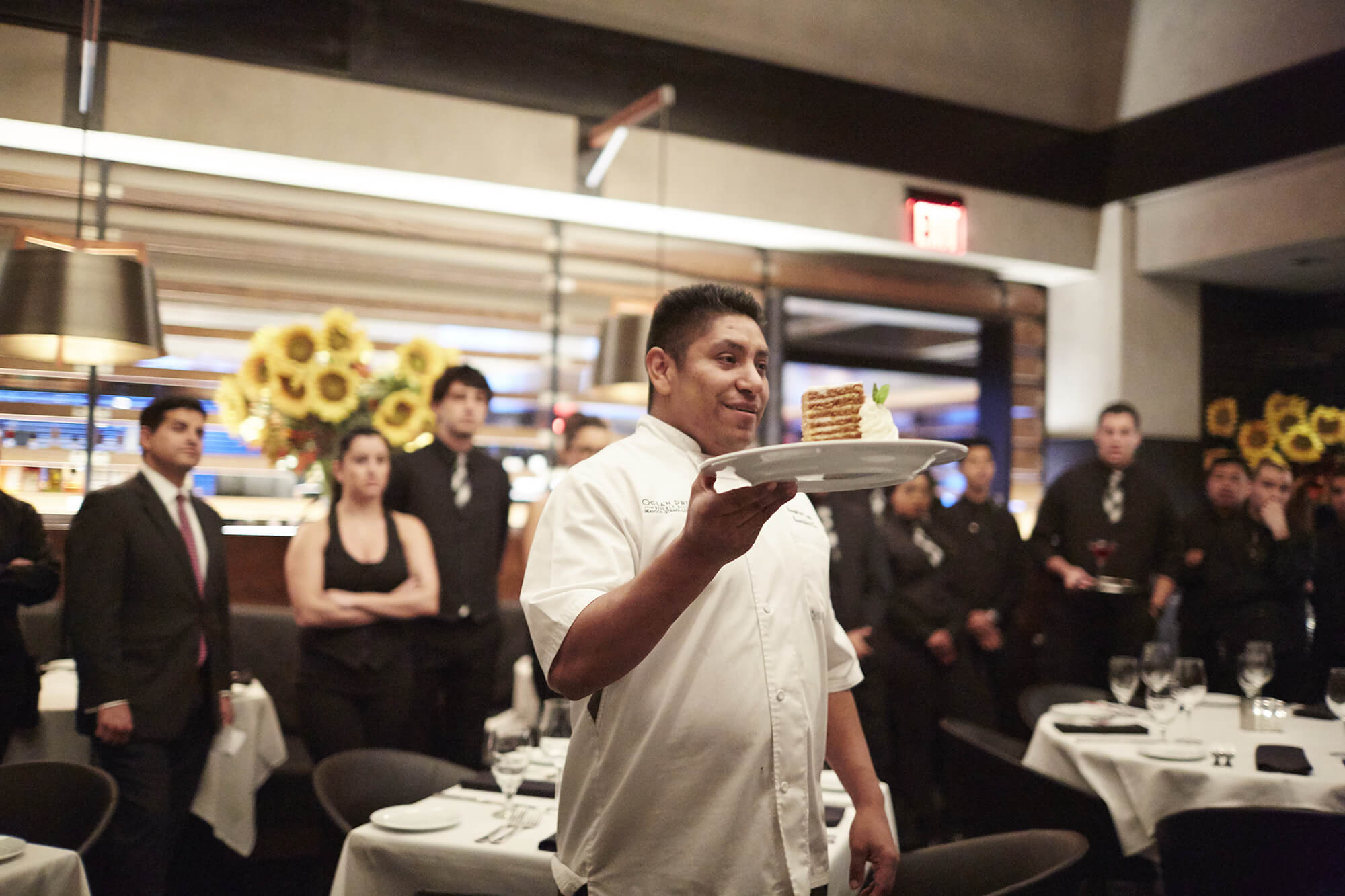 Ocean prime chef holding up a plate inside restaurant